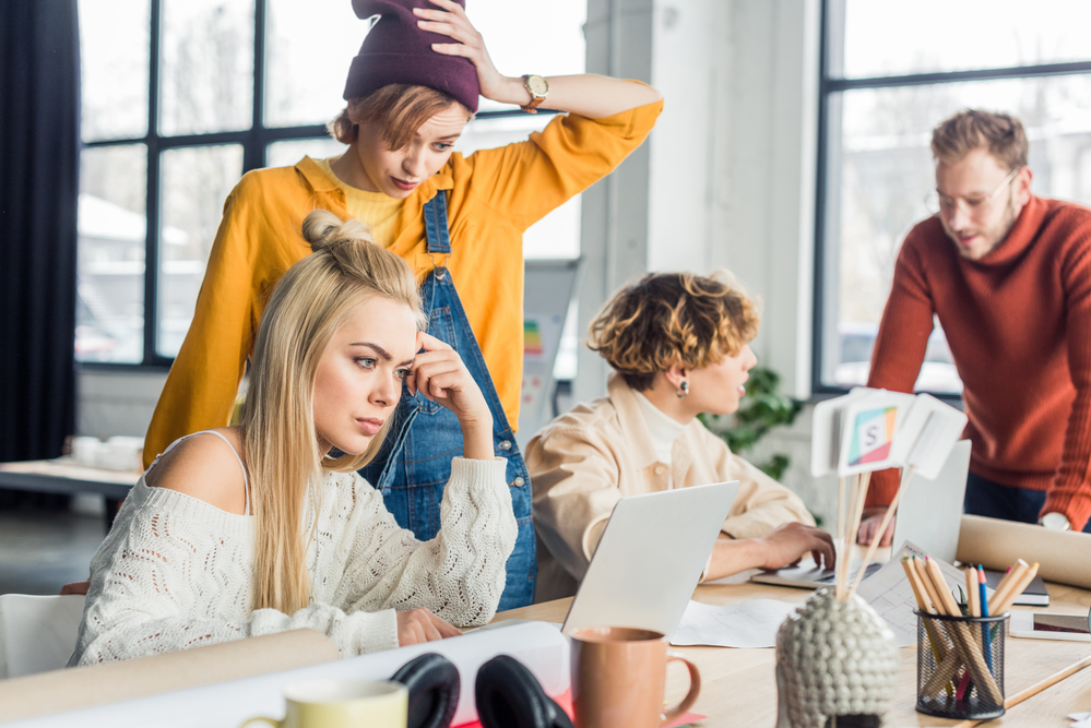 concentrated-female-and-male-casual-businesspeople-working-on-startup-project-with-laptop-in-loft-office